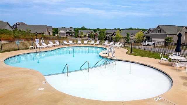 community pool featuring a residential view, a patio, and fence