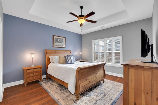 bedroom featuring baseboards, a raised ceiling, visible vents, and dark wood-style flooring