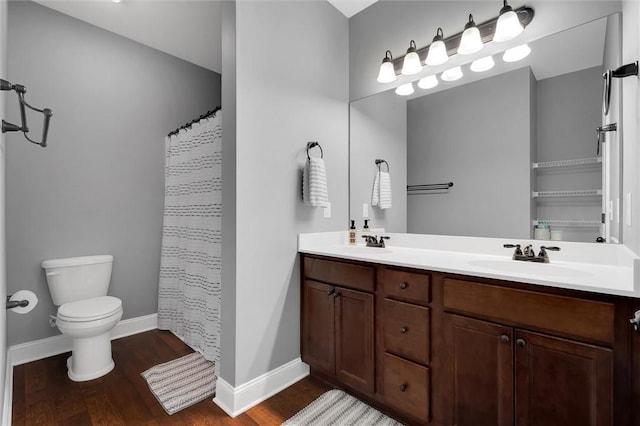 bathroom with a sink, toilet, wood finished floors, and double vanity