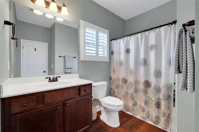 full bathroom with curtained shower, baseboards, toilet, wood finished floors, and vanity