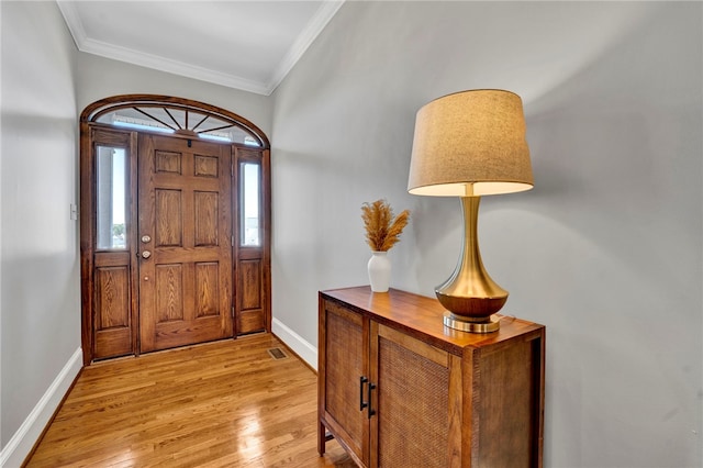 entryway with light wood-type flooring, baseboards, and ornamental molding