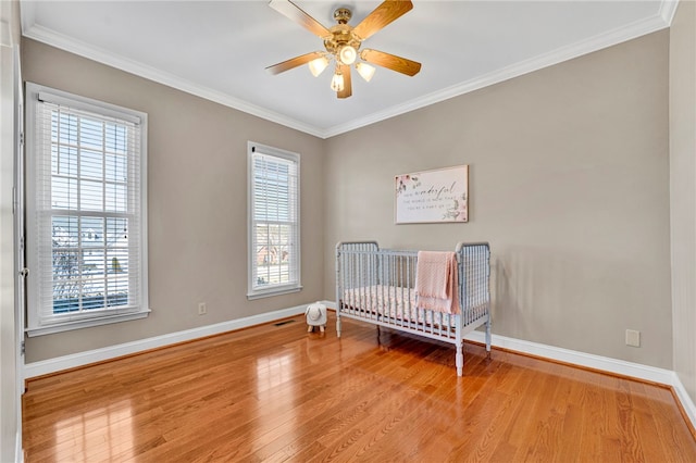 bedroom featuring visible vents, wood finished floors, baseboards, and ornamental molding