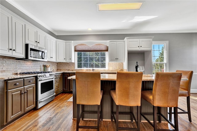 kitchen featuring a center island, stainless steel appliances, crown molding, and light wood-style floors