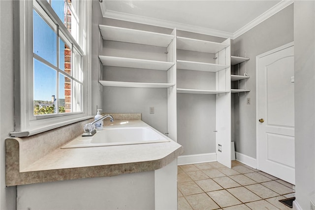 laundry room with light tile patterned flooring, crown molding, baseboards, and a sink