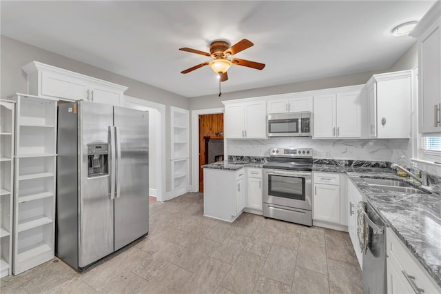 kitchen featuring dark stone countertops, a sink, appliances with stainless steel finishes, white cabinetry, and backsplash