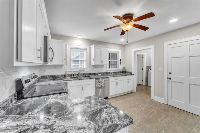 kitchen featuring a sink, stainless steel appliances, dark stone counters, white cabinets, and decorative backsplash