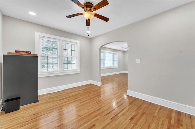 interior space featuring visible vents, baseboards, light wood-style flooring, arched walkways, and ceiling fan