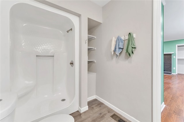 bathroom with visible vents, baseboards, walk in shower, toilet, and wood finished floors