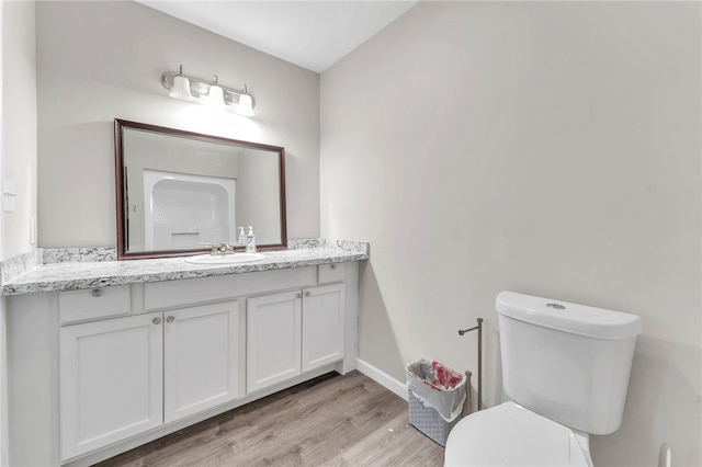 bathroom featuring baseboards, toilet, wood finished floors, and vanity