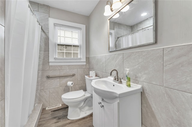 full bathroom with a shower with curtain, toilet, wood finished floors, tile walls, and vanity