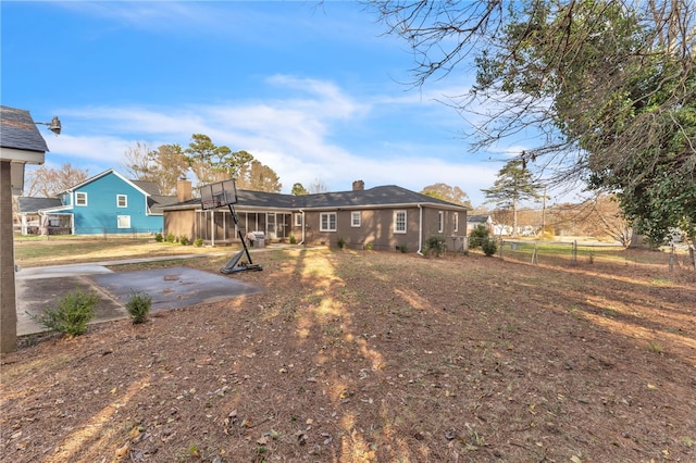 back of property with fence, a patio, and a sunroom