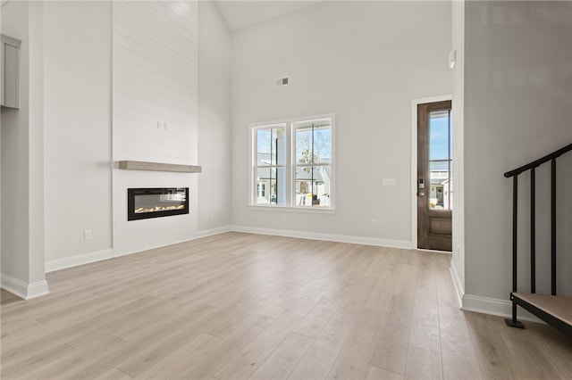 unfurnished living room with visible vents, baseboards, stairway, light wood-style flooring, and a fireplace