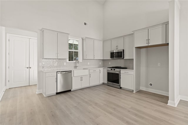 kitchen featuring visible vents, a sink, backsplash, stainless steel appliances, and light countertops