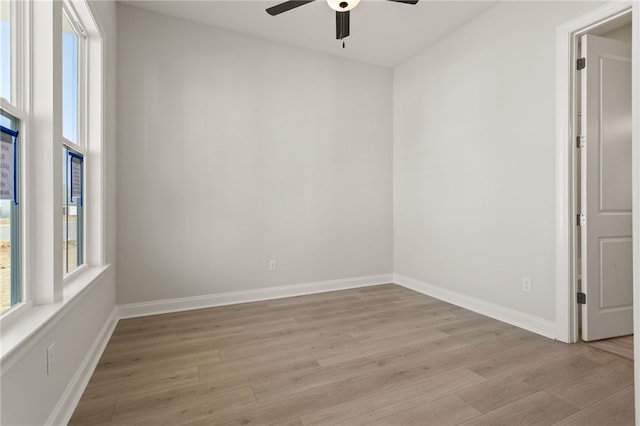 empty room with a ceiling fan, baseboards, and light wood finished floors