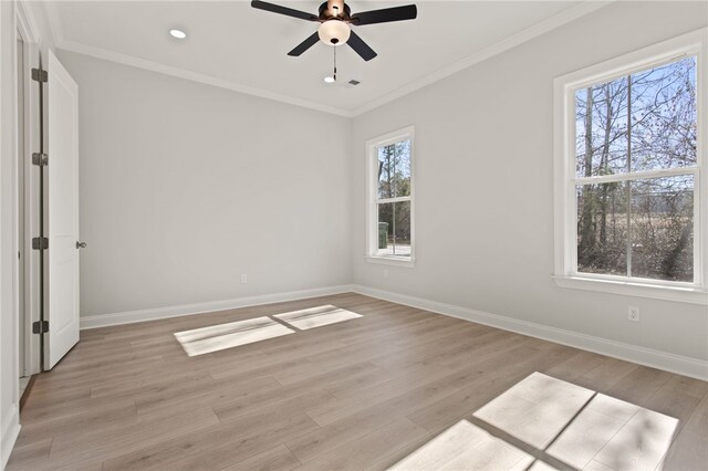 empty room featuring crown molding, baseboards, and light wood-type flooring