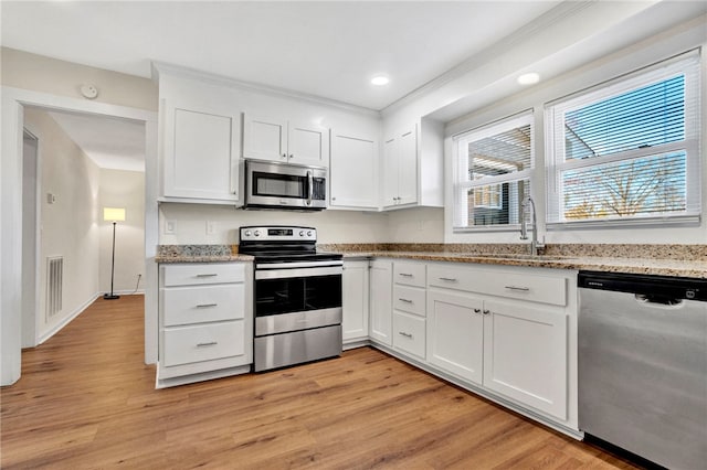 kitchen with white cabinetry, stainless steel appliances, and light wood-type flooring