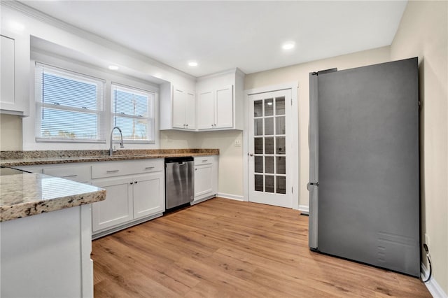 kitchen with white cabinets, light stone counters, light wood-type flooring, and appliances with stainless steel finishes