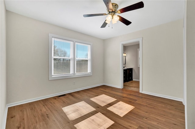 spare room featuring visible vents, a ceiling fan, baseboards, and wood finished floors