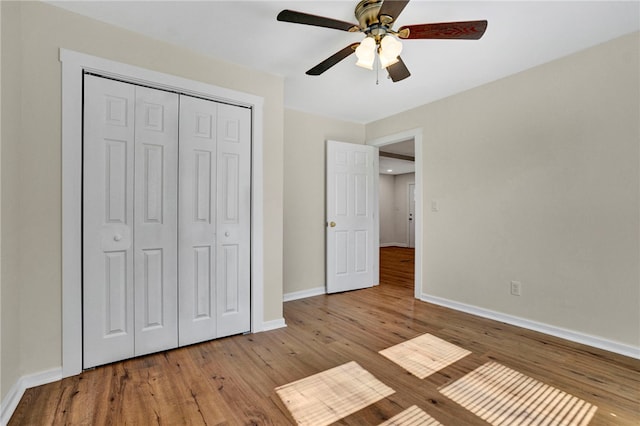 unfurnished bedroom with ceiling fan, a closet, baseboards, and wood finished floors