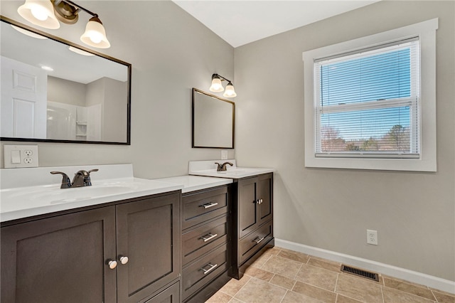 full bath with a sink, visible vents, baseboards, and double vanity