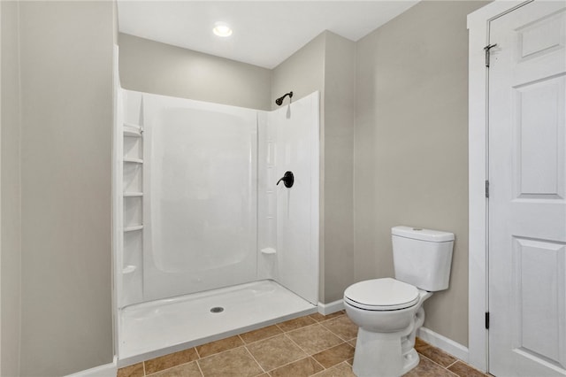 bathroom featuring tile patterned floors, baseboards, toilet, and walk in shower