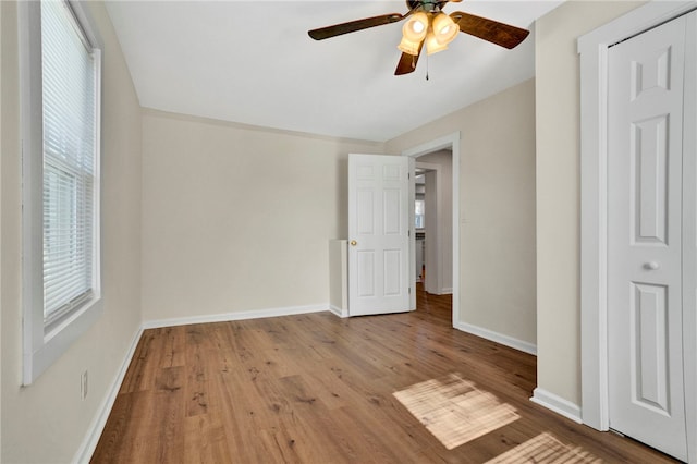 unfurnished bedroom with wood finished floors, baseboards, and ceiling fan