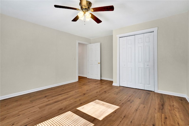 unfurnished bedroom featuring a closet, baseboards, wood finished floors, and a ceiling fan