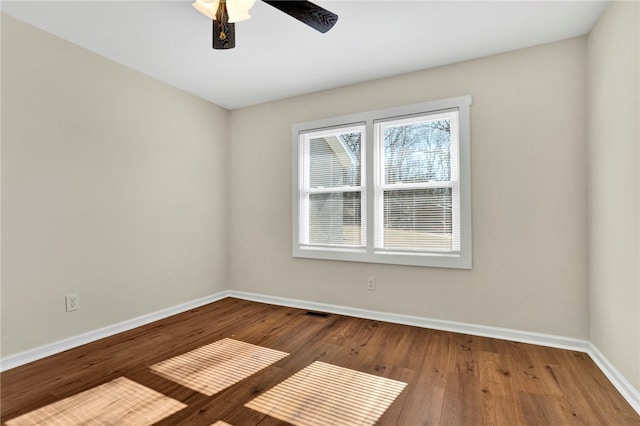 empty room with ceiling fan, visible vents, baseboards, and wood finished floors