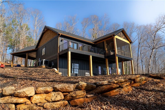 view of side of home with board and batten siding and a sunroom