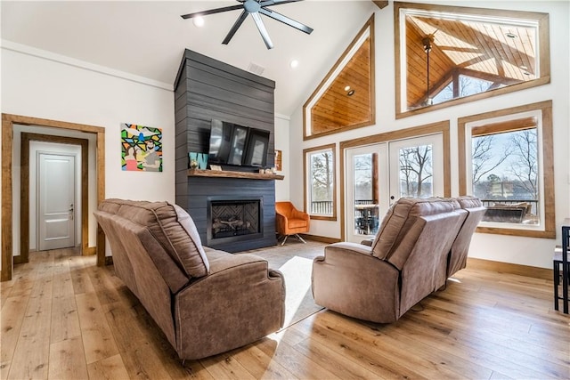 living room featuring light wood-style flooring, french doors, a large fireplace, and ceiling fan