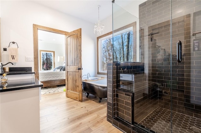 full bathroom with a soaking tub, a shower stall, ensuite bathroom, and wood finished floors