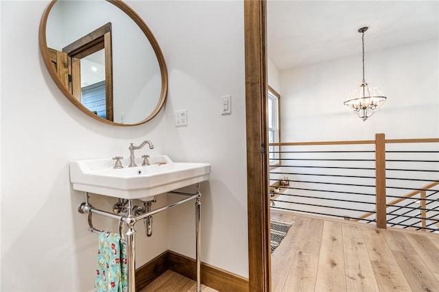 bathroom with a notable chandelier, baseboards, and hardwood / wood-style flooring