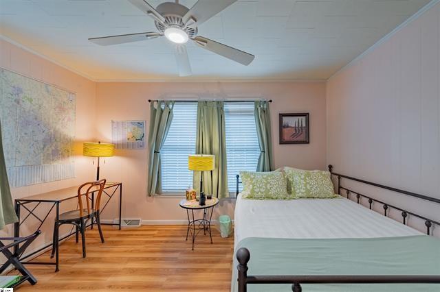 bedroom with visible vents, crown molding, and wood finished floors