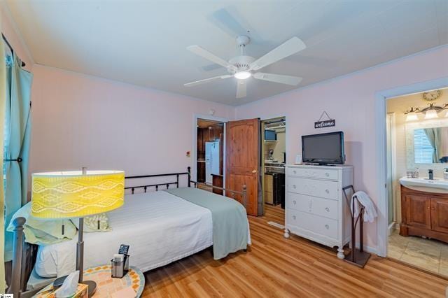 bedroom with ceiling fan, light wood-type flooring, and connected bathroom