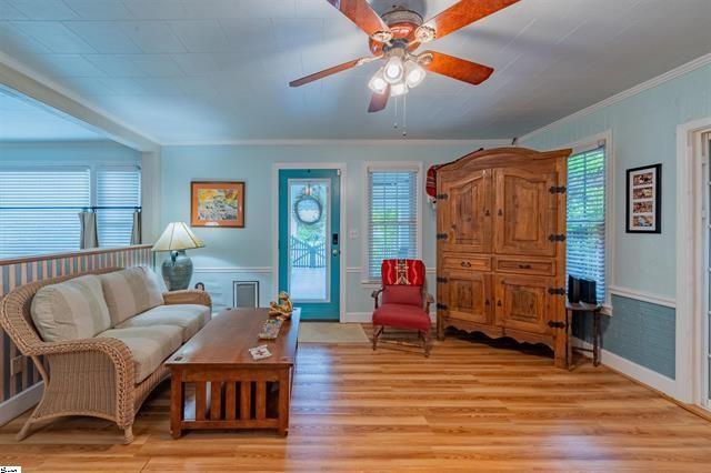 living room featuring a healthy amount of sunlight, light wood finished floors, and wainscoting