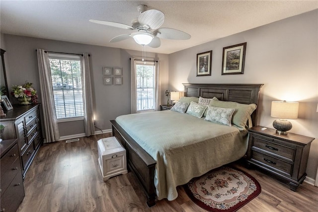 bedroom featuring multiple windows, dark wood-style floors, and baseboards