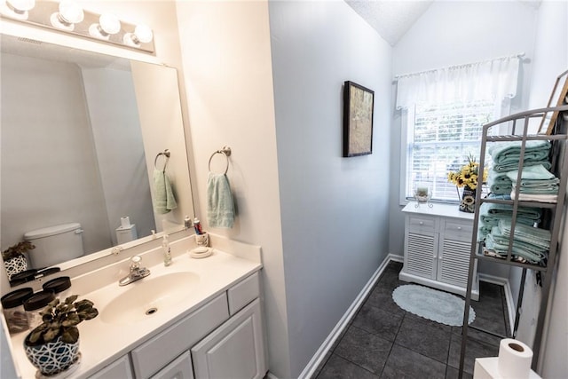 bathroom featuring vanity, vaulted ceiling, toilet, and baseboards