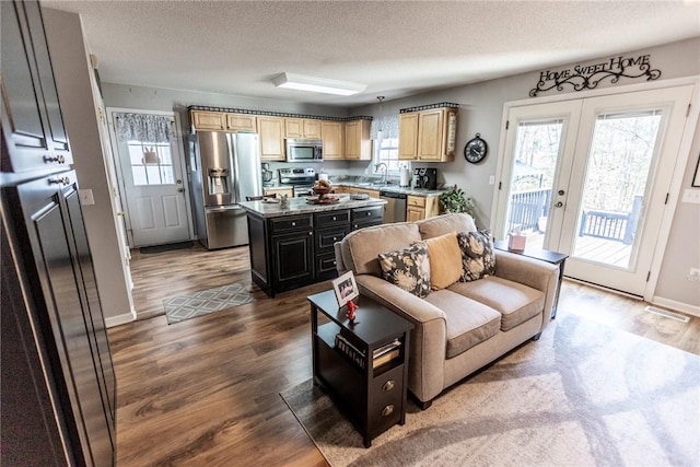 living room featuring french doors, baseboards, a textured ceiling, and wood finished floors