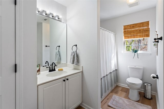 full bath featuring visible vents, toilet, wood finished floors, baseboards, and vanity