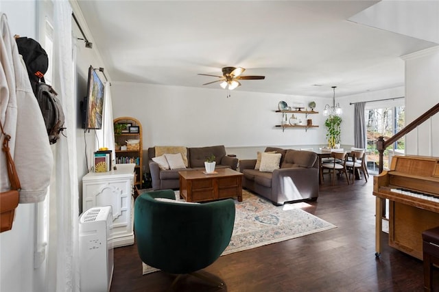 living area with dark wood-type flooring, stairway, crown molding, and ceiling fan