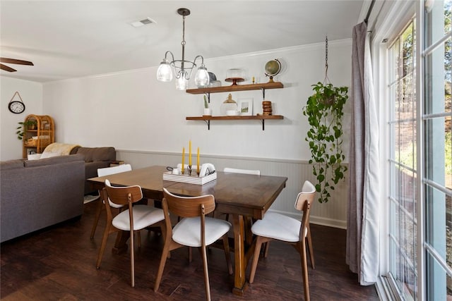 dining area with a wainscoted wall, visible vents, a ceiling fan, crown molding, and dark wood-style flooring