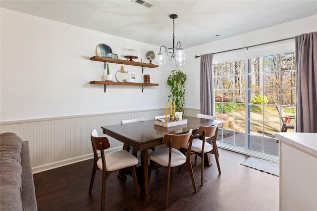 dining space with visible vents, a chandelier, a wainscoted wall, ornamental molding, and wood finished floors