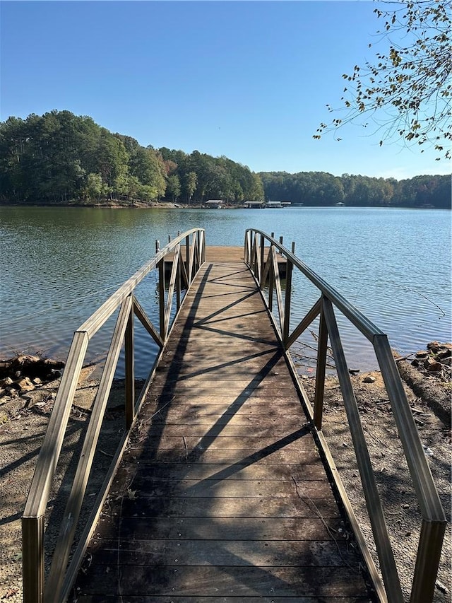 view of dock featuring a forest view and a water view