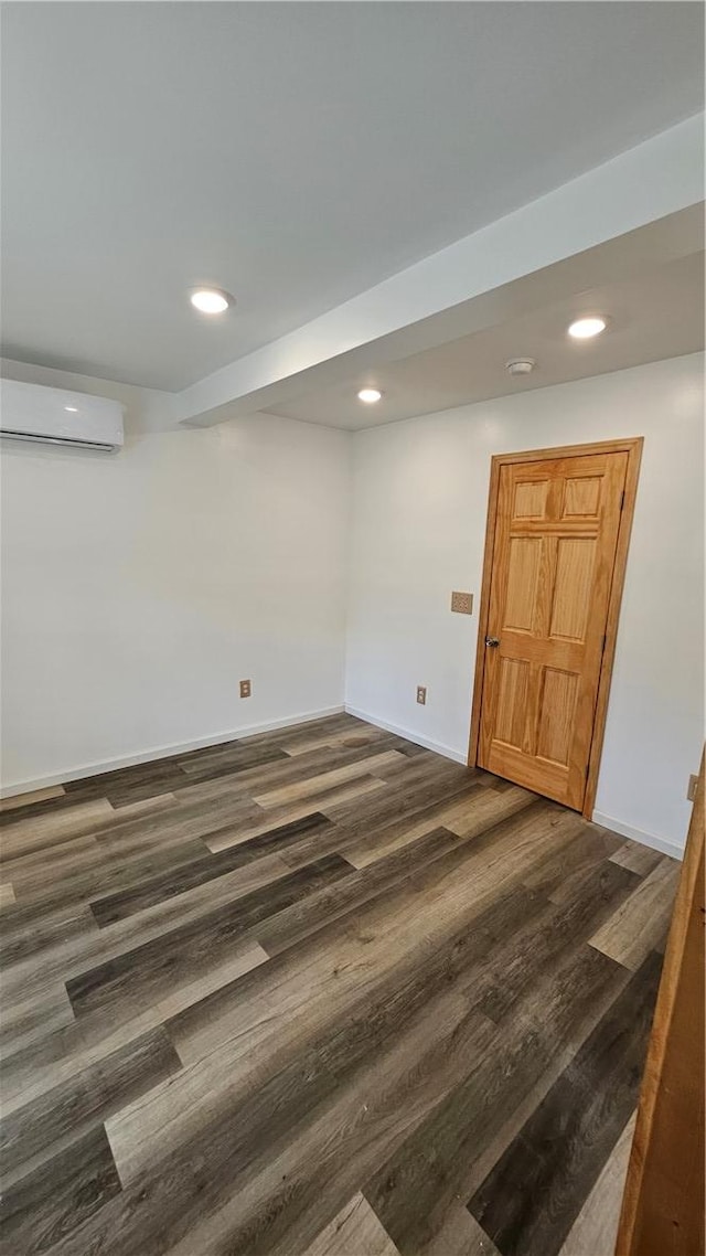 basement with a wall mounted air conditioner, baseboards, dark wood-type flooring, and recessed lighting