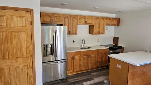 kitchen featuring dark wood-type flooring, light countertops, appliances with stainless steel finishes, brown cabinetry, and a sink