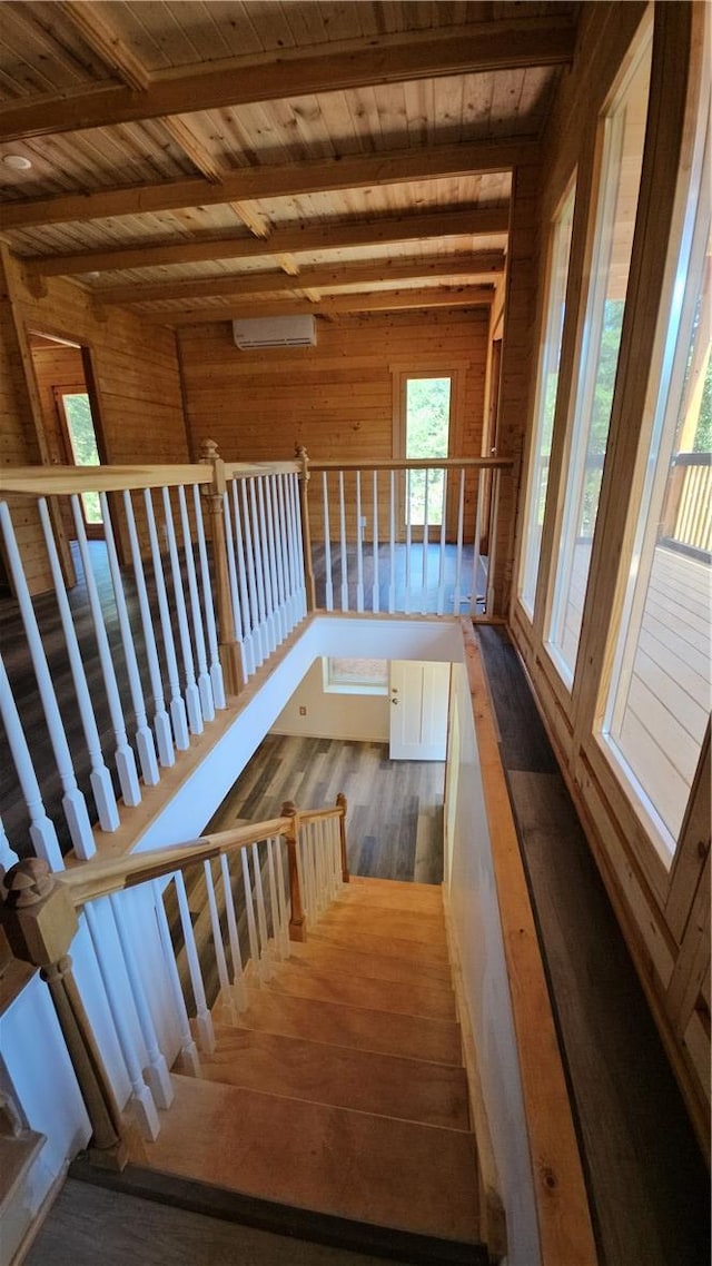 stairs featuring beamed ceiling, wood walls, a wall unit AC, wooden ceiling, and wood finished floors