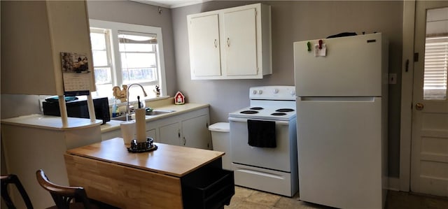 kitchen with white appliances, white cabinets, light countertops, and a sink