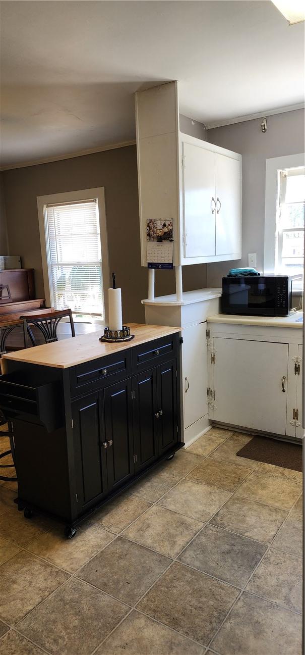 kitchen with crown molding, dark cabinets, black microwave, and light countertops