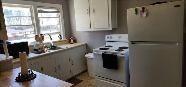 kitchen featuring a sink, white appliances, white cabinets, and light countertops