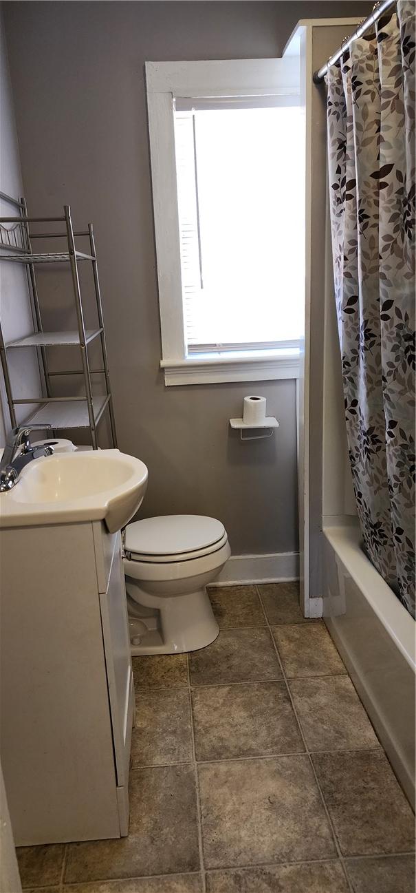 full bathroom with vanity, toilet, baseboards, and shower / bath combo with shower curtain